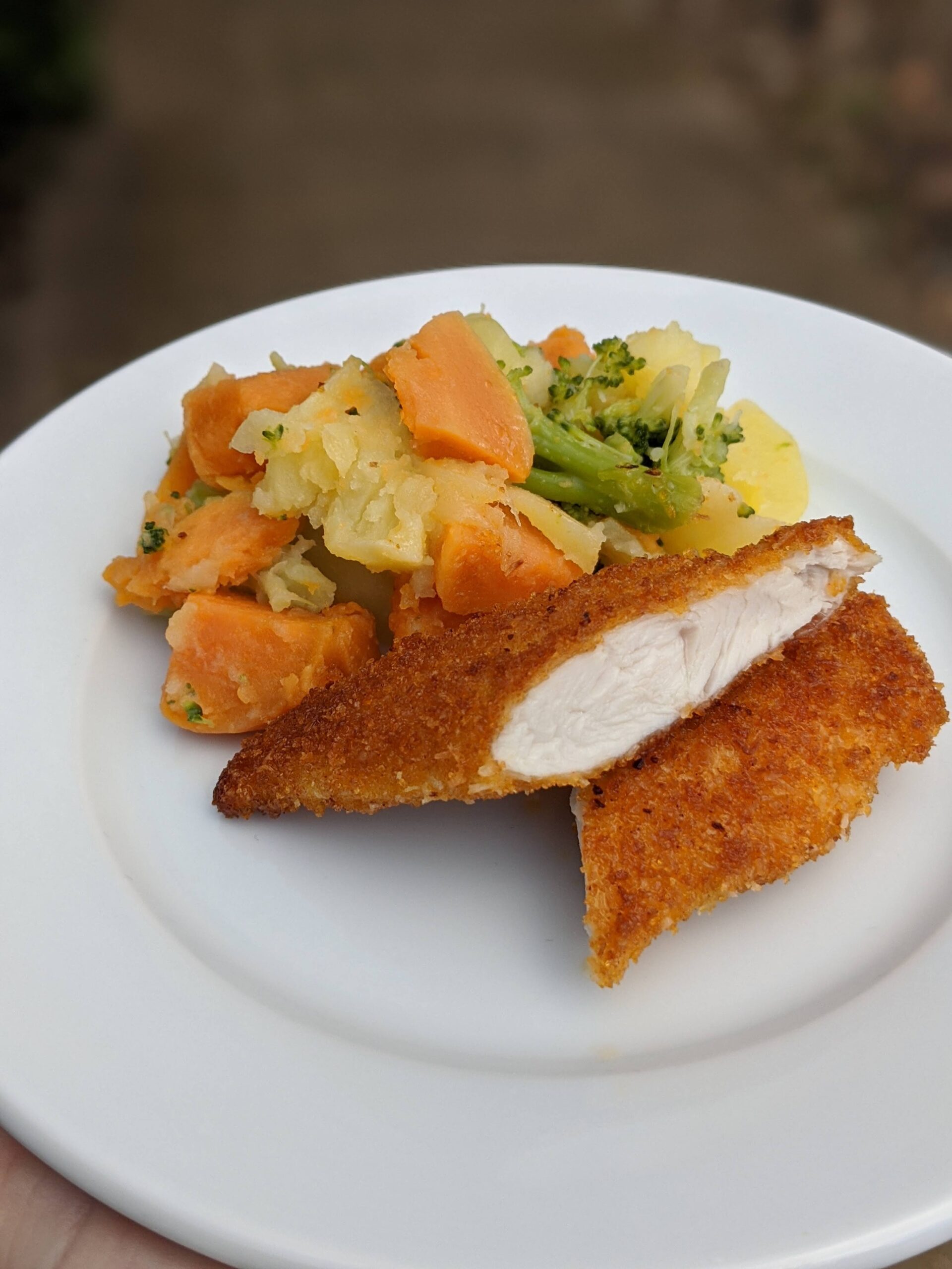 Coconut crusted chicken schnitzel served with vegetable mash